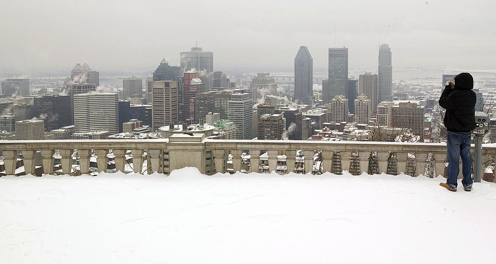 A man takes a picture of the Montreal skyline from the top of Mount Royal