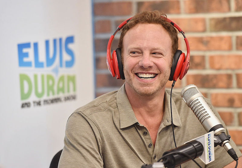 Ian Ziering smiles and wears red headphone while sitting in front of a microphone during a radio interview. Ian Ziering smiles and wears red headphone while sitting in front of a microphone during a radio interview.