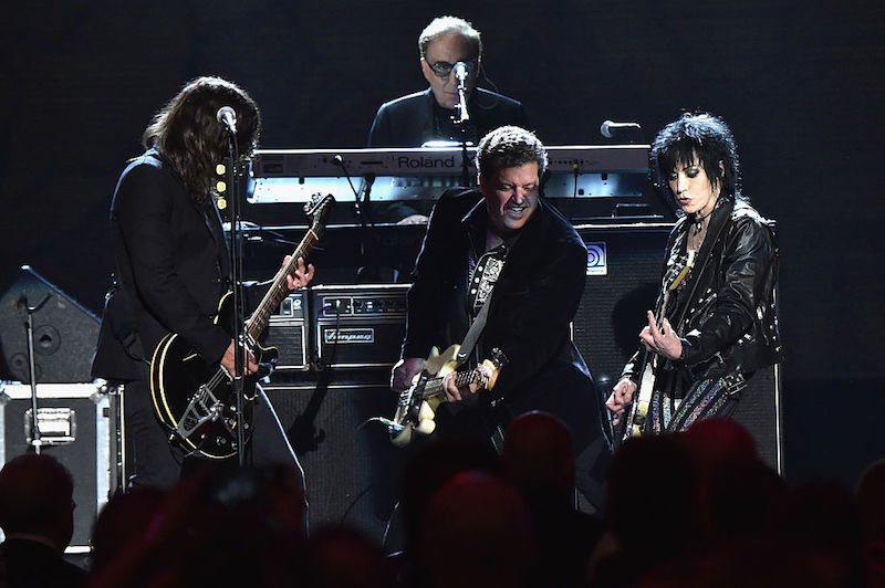 Joan Jett playing guitar and performing on stage with her band. Joan Jett playing guitar and performing on stage with her band.