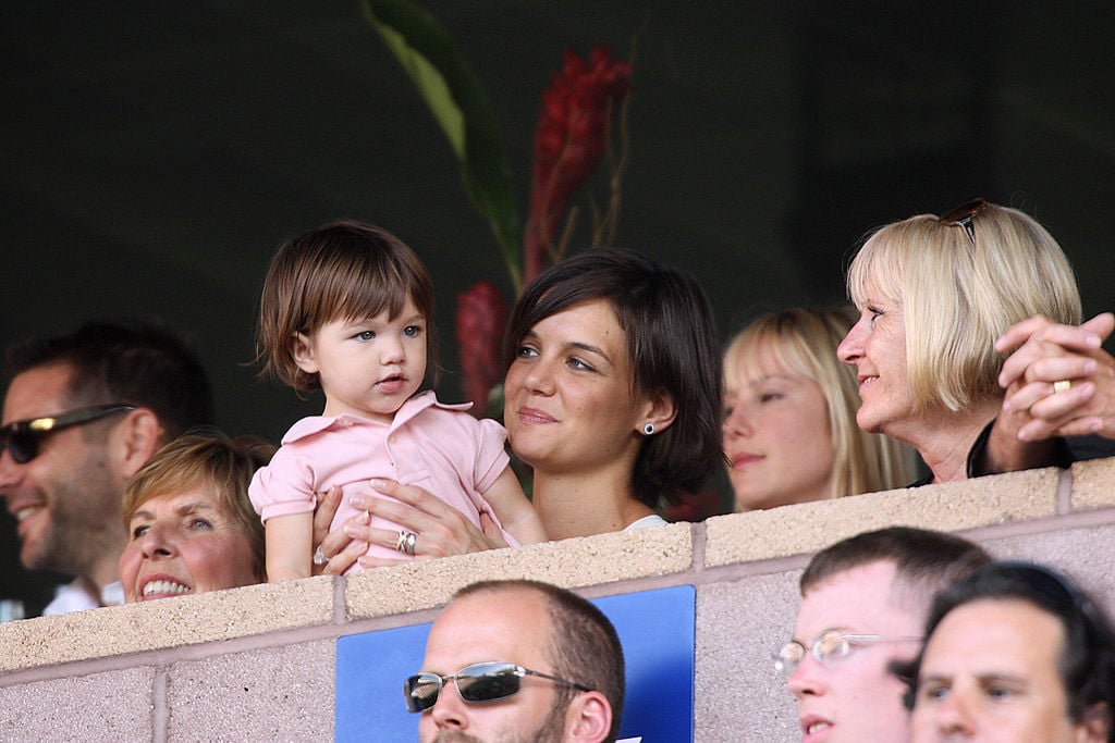 Katie Holmes holds her daughter Suri Cruise as they watch a soccer game.