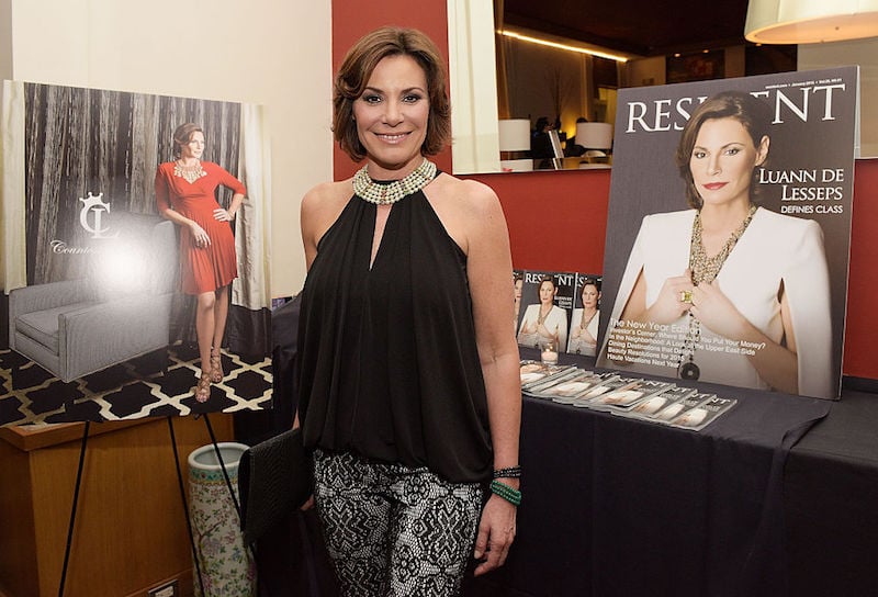 Luann de Lesseps posing in front of a table and photos of herself.