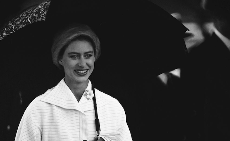 Princess Margaret stands under an umbrella. 