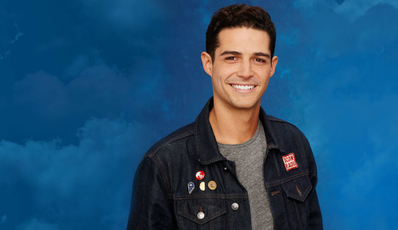 Wells Adams smiles in front of a blue background.