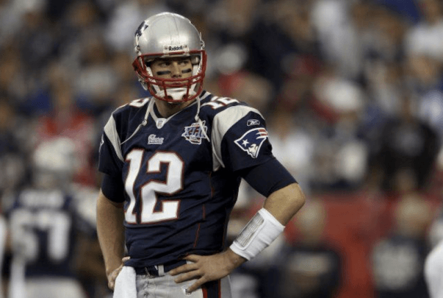 Tom Brady stands on a football field. Tom Brady stands on a football field.