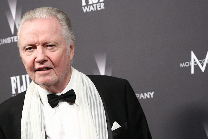 Voight wearing a tuxedo and posing on a red carpet. Voight wearing a tuxedo and posing on a red carpet.