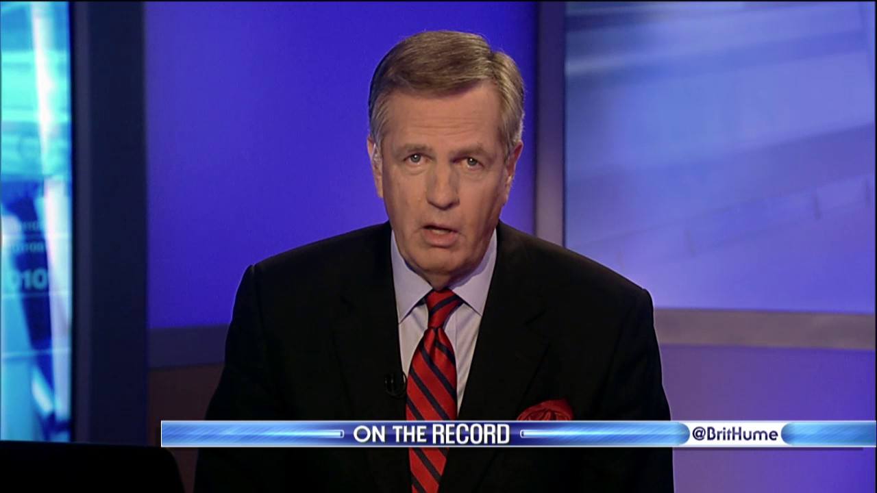 Brit Hume reporting behind a news desk in a red and black striped tie and black suit.