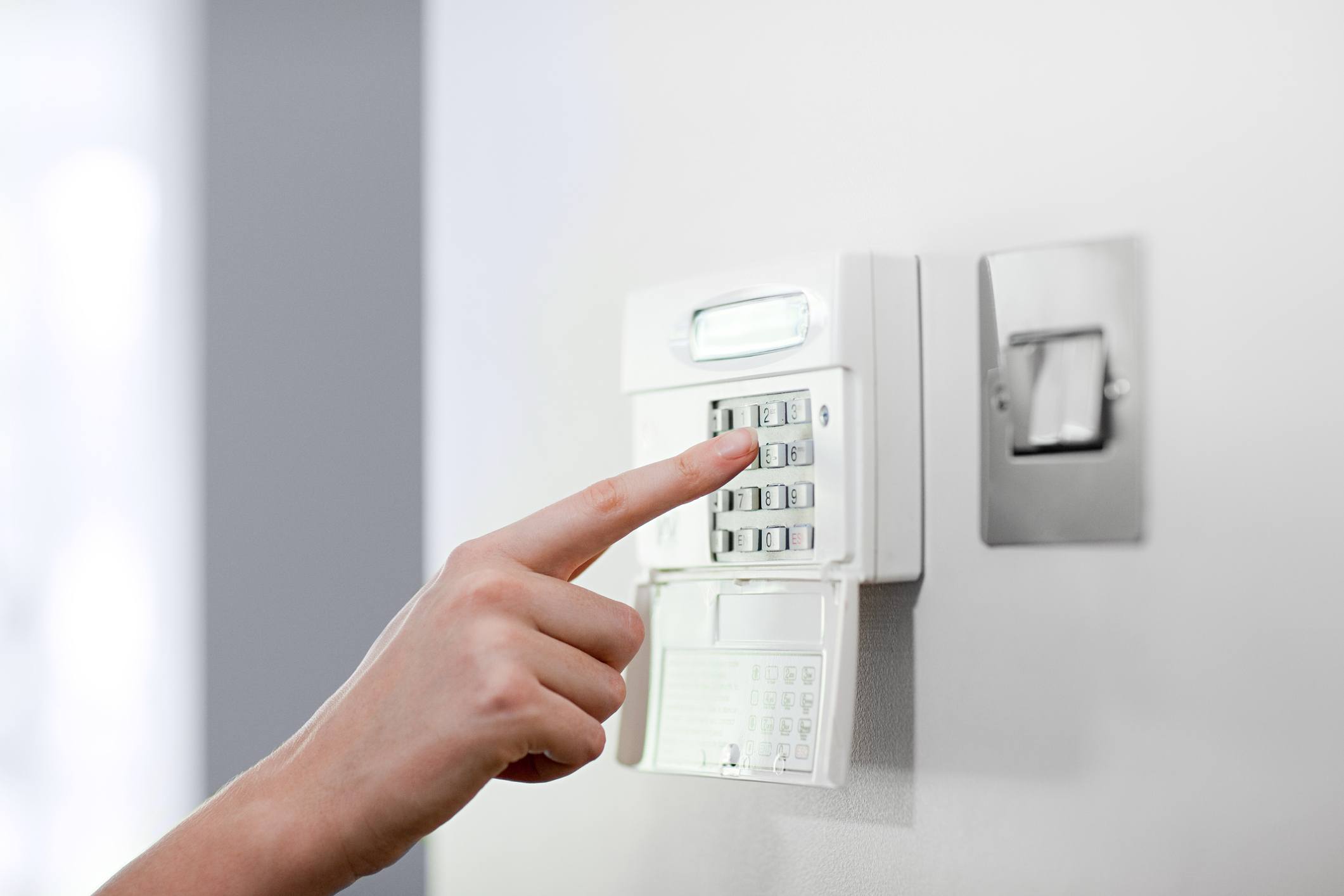Woman setting burglar alarm