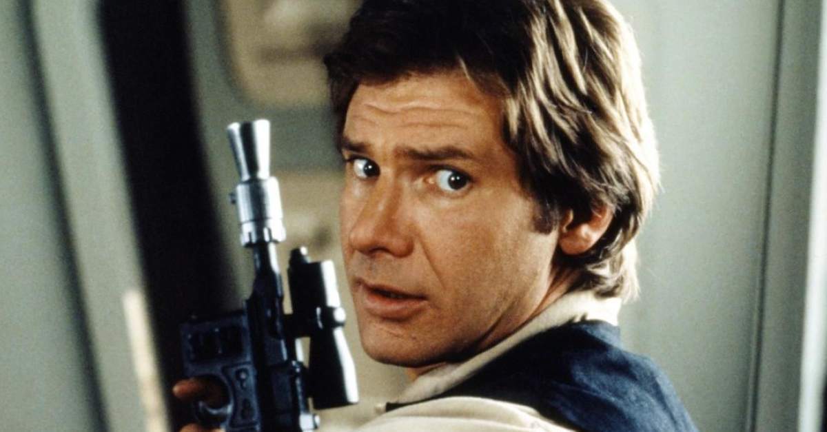 Harrison Ford holds a weapon and looks over his shoulder Han Solo