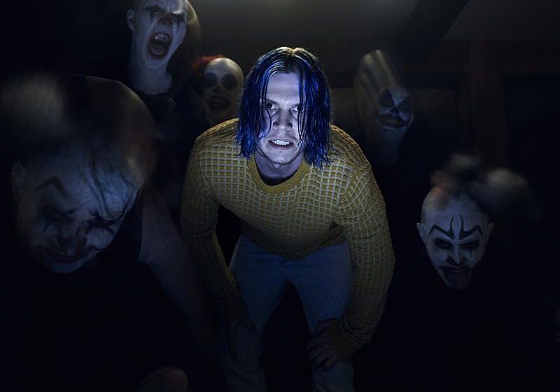 Kai Anderson in a yellow sweater surrounded by creepy clowns Kai Anderson in a yellow sweater surrounded by creepy clowns