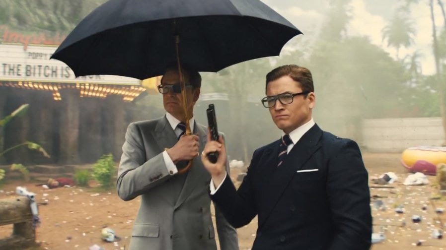Colin Firth and Taron Egerton stand next to each other while holding a gun and umbrella Colin Firth and Taron Egerton stand next to each other while holding a gun and umbrella