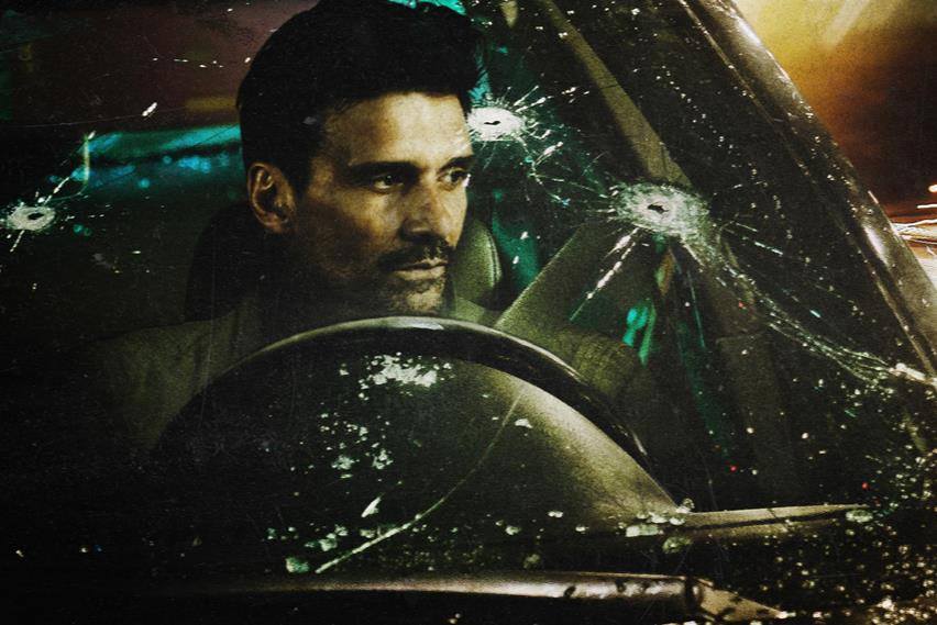 A man sits behind the wheel of a car with a bullet-ridden windshield A man sits behind the wheel of a car with a bullet-ridden windshield
