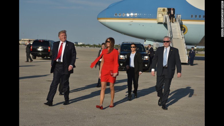 Donald and Melania Trump walk away from Air Force One on the tarmac surrounded by 4 Secret Service agents