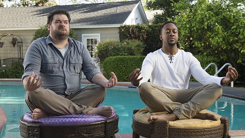 Two men sit next to each other in meditation poses