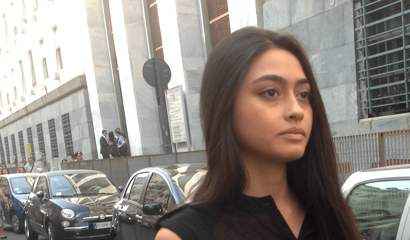Ambra Battilana Gutierrez standing in a black dress in front of a building.