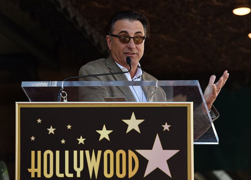 Andy Garcia speaking to the public in front of a podium. Andy Garcia speaking to the public in front of a podium.