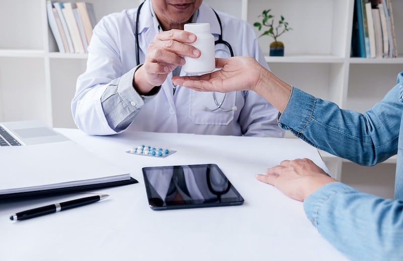doctor handing medications to a woman doctor handing medications to a woman
