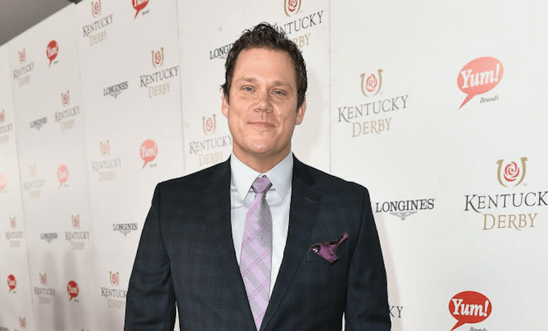 Bob Guiney standing in a purple tie and plaid suit.