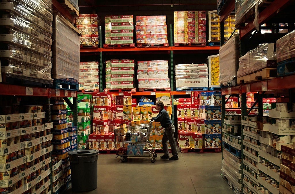 Shopper pushes cart through Costco store Shopper pushes cart through Costco