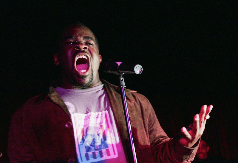 Craig muMs Grant performing in front of a microphone. Craig muMs Grant performing in front of a microphone.