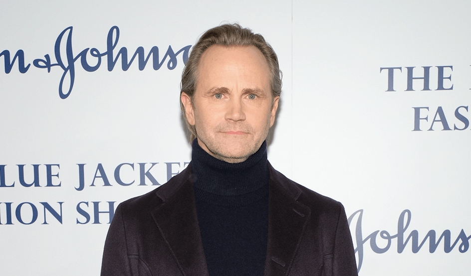 Lee Tergesen standing in a black turtleneck and dark jacket and staring straight ahead. Lee Tergesen standing in a black turtleneck and dark jacket and staring straight ahead.