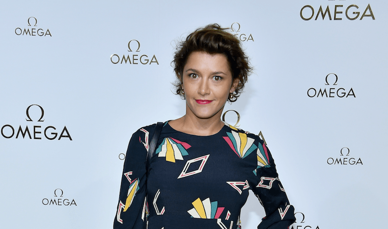 Emma de Caunes standing in a colorful dress with her hand on her hip. Emma de Caunes standing in a colorful dress with her hand on her hip.