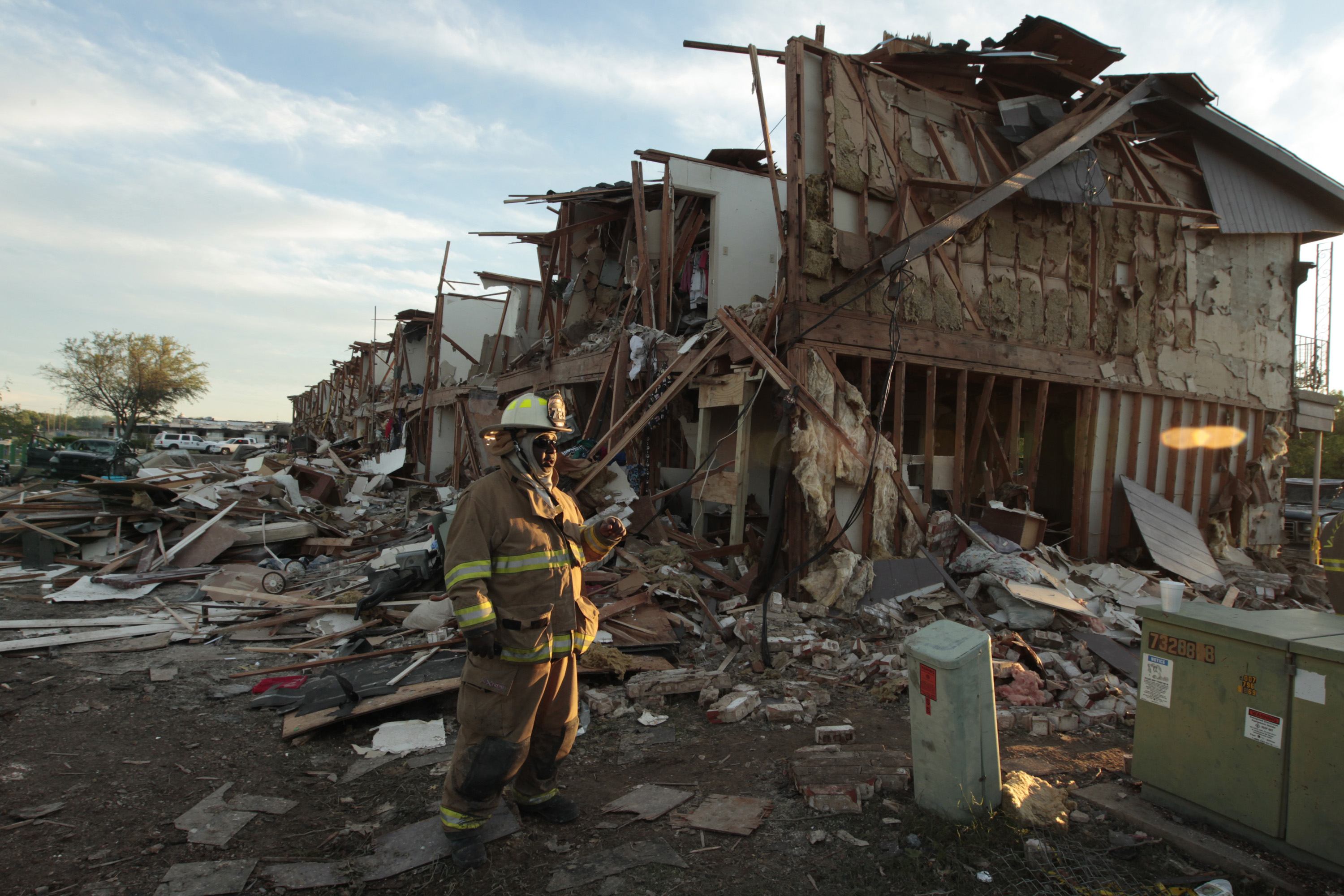 Stands among a destroyed building caused by an explosion