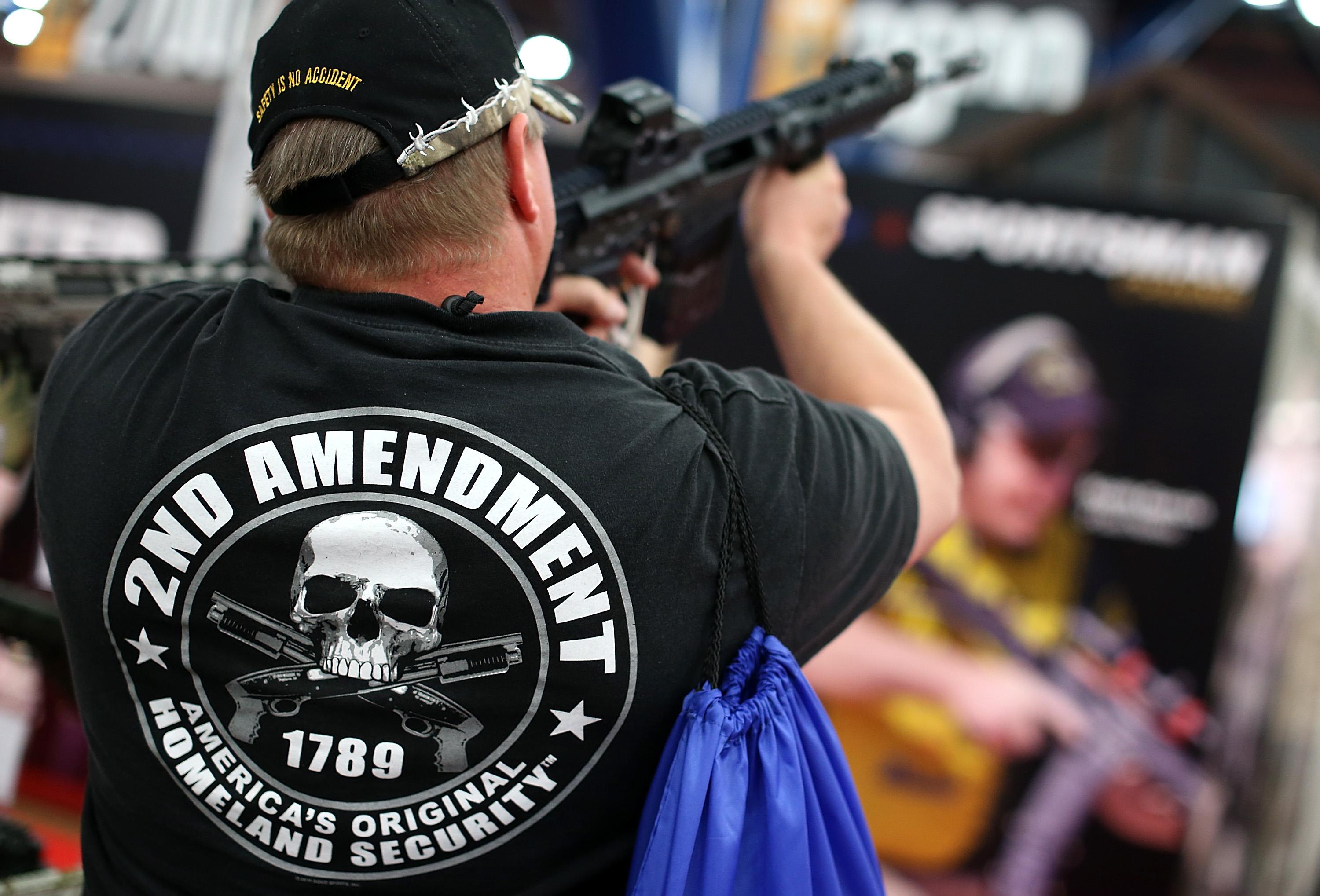 An attendee wears a 2nd amendment shirt while inspecting an assault rifle during the 2013 NRA Annual Meeting and Exhibits at the George R. Brown Convention Center