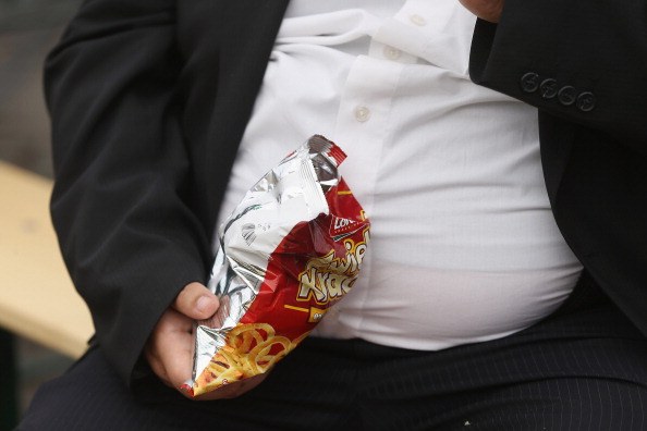 obese man eats a bag of chips obese man with chips