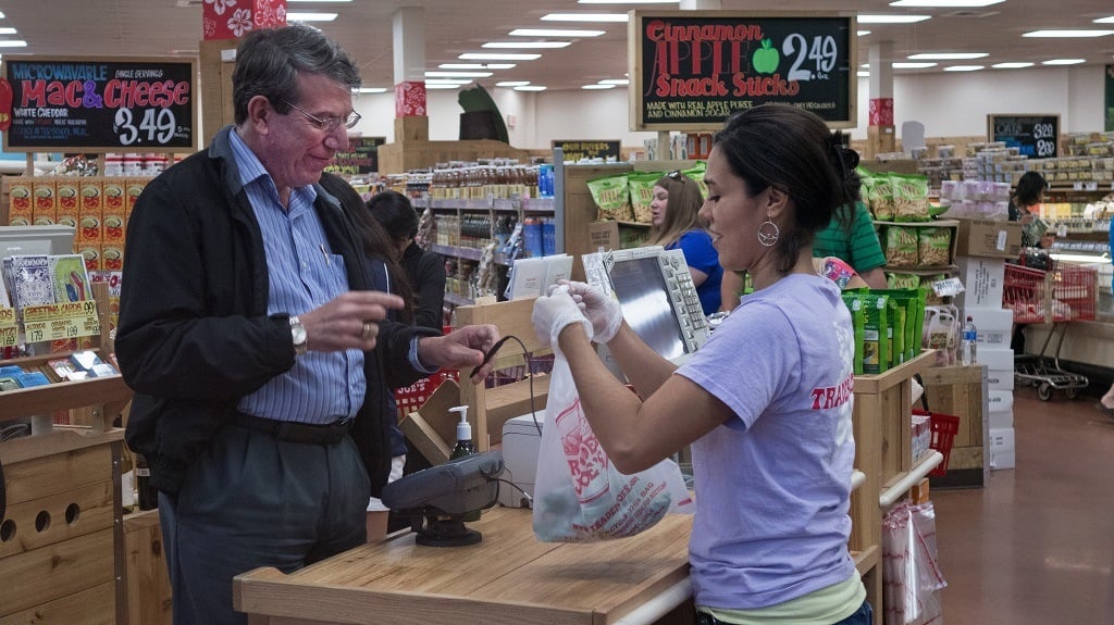 An unidentified man (L) pays for groceries at Trader Joe's in Centreville, Virginia, on September 13, 2013. The national supermarket chain informed part-time employees that it would end health insurance benefits in 2014 for employees who work less than 30 hours a week, sending them instead to the new public insurance marketplaces with an extra 500 USD to help purchase coverage. Under the Affordable Care Act (ACA), or "Obamacare", companies are not required to offer health coverage to their part-time workers. AFP PHOTO/Paul J. Richards (Photo credit should read PAUL J. RICHARDS/AFP/Getty Images)