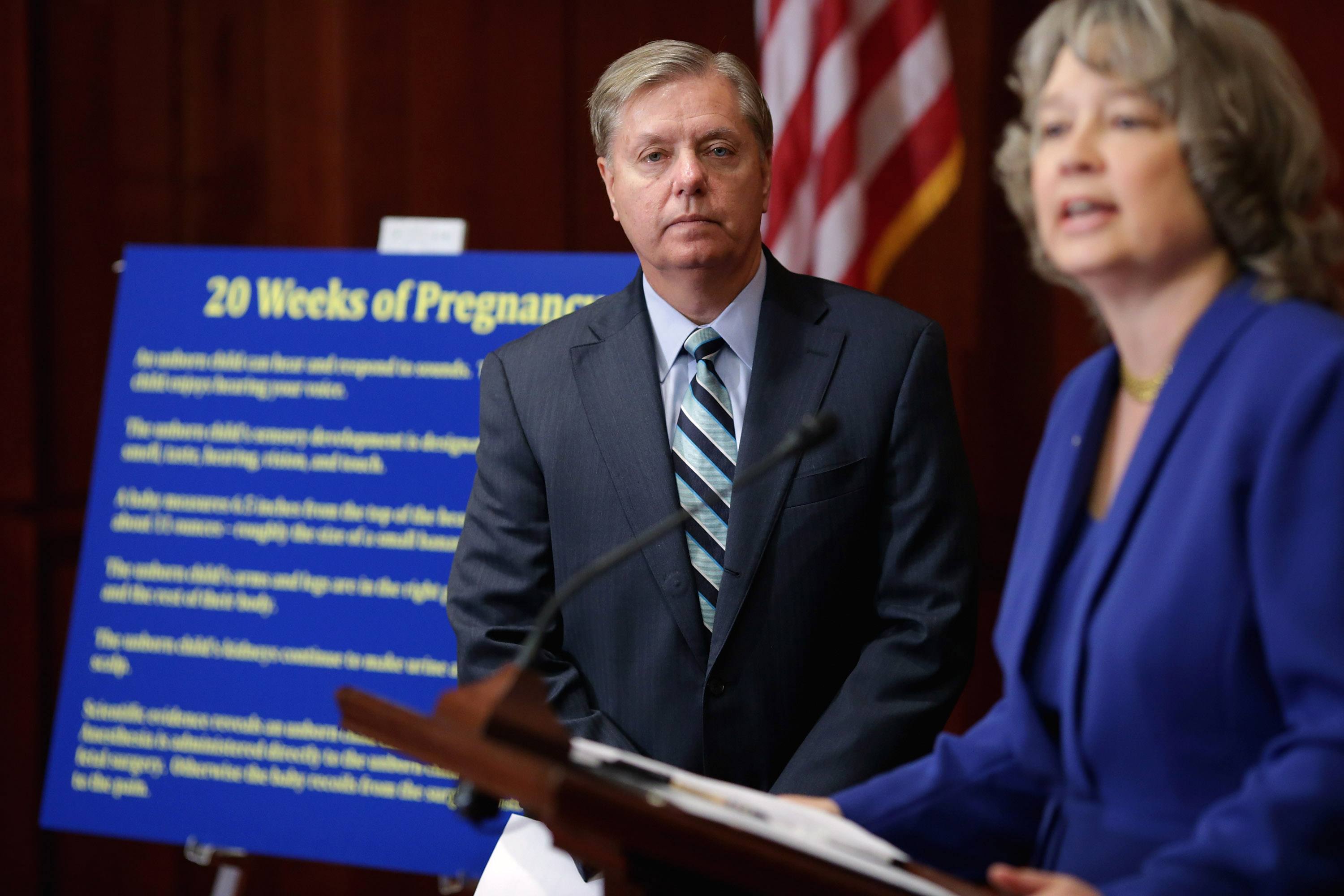 Sen. Lindsey Graham (R-SC) (L) listens to National Right to Life Committee President Carol Tobias speak while standing infront of a board that explains the Pain-Capable bill of banning abortions after 20 weeks