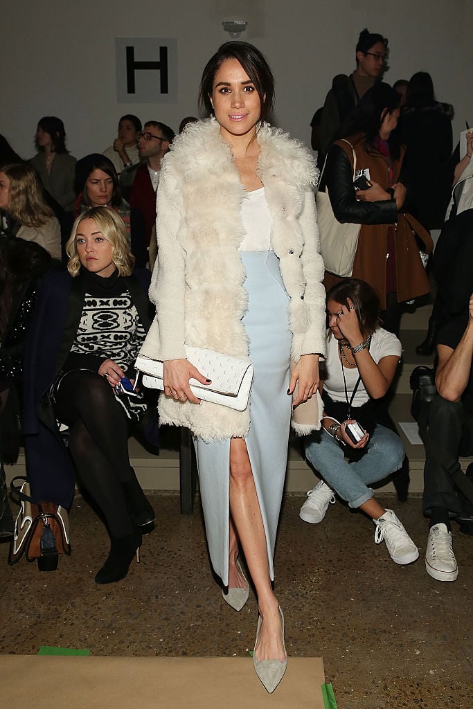 Meghan Markle posing in a fur coat in front of a crowd of people. Meghan Markle posing in a fur coat in front of a crowd of people.