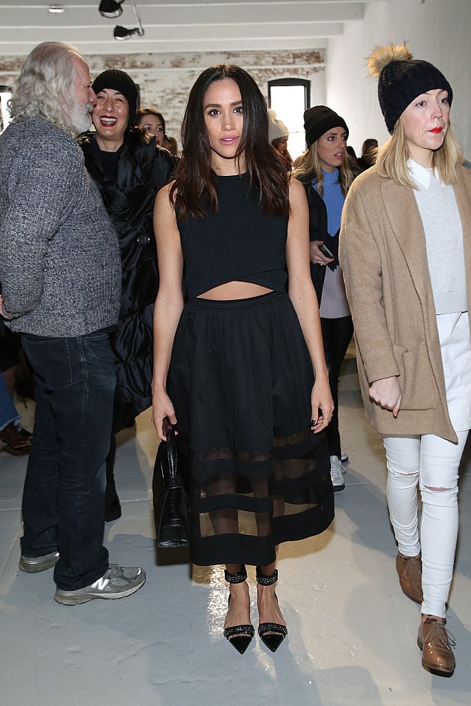 Meghan Markle posing in front of a crowd of people in a black midi dress Meghan Markle posing in front of a crowd of people in a black midi dress