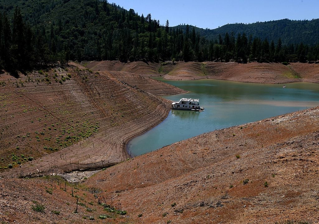 A lone houseboat beside an almost dry section of the Shasta Lake reservoir A lone houseboat beside an almost dry section of the Shasta Lake reservoir