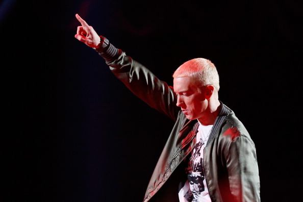Eminem in a t-shirt and jacket against a black background points to the sky Eminem in a t-shirt and jacket against a black background points to the sky