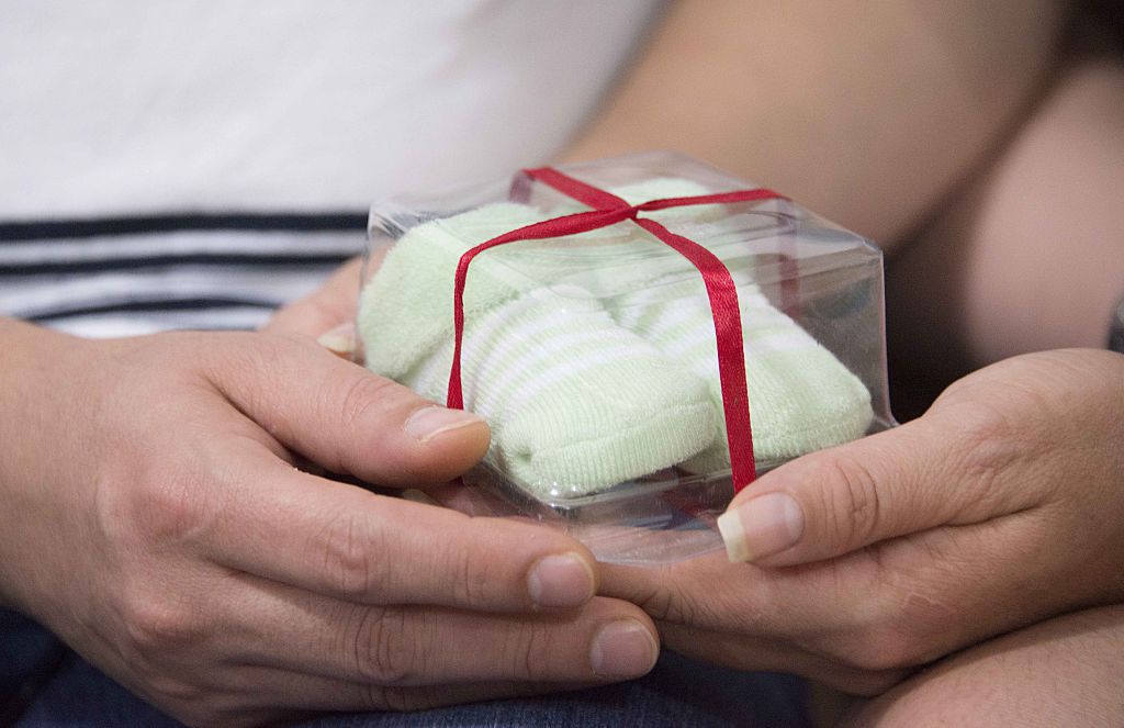 a couple holds a pair of booties baby booties and hands
