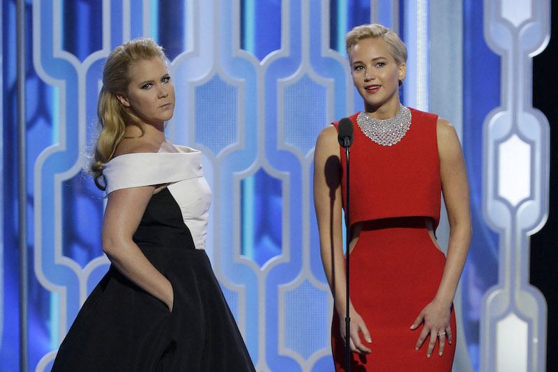 Amy Schumer and Jennifer Lawrence stand next to each other on stage