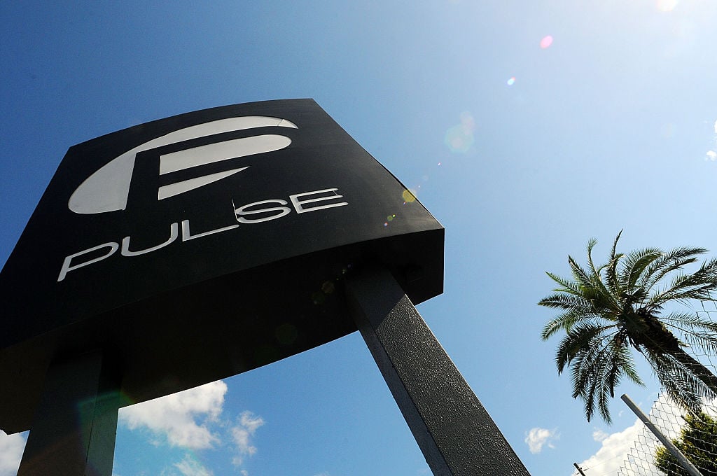 the black and white sign outside Pulse Nightclub against a blue sky and a palm tree