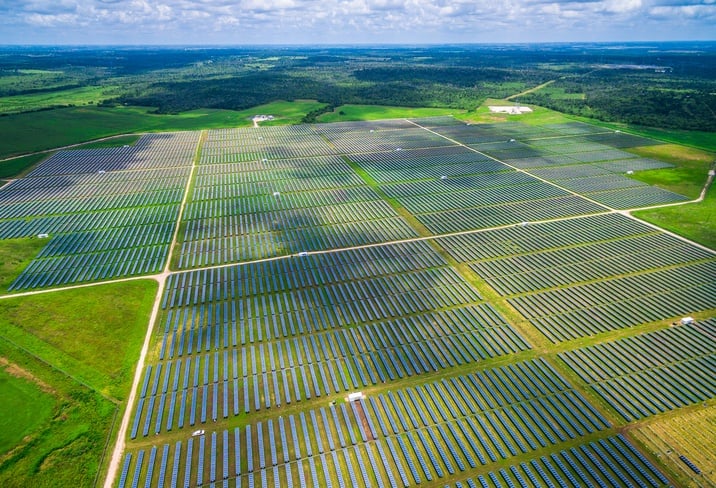 A large solar array over green fields with a blue sky