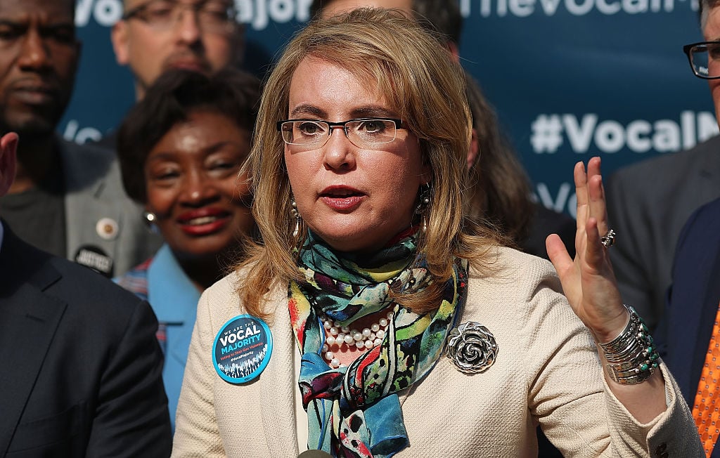 Gabby Giffords in glasses, a tan jacket, and colorful scarf