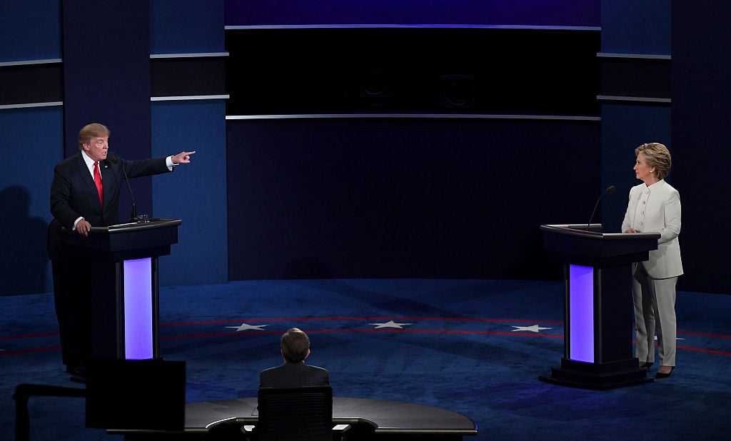 Donald Trump points at Hillary Clinton (in white) onstage at the last debate, in a dark room Donald Trump points at Hillary Clinton onstage in white at the last debate, in a dark room