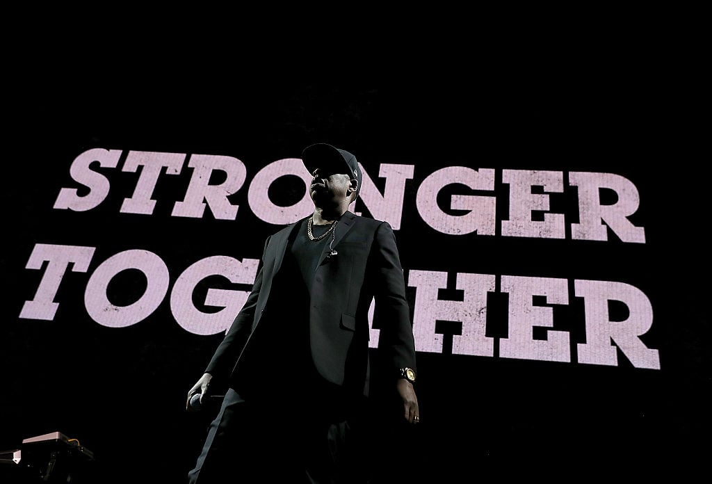 Jay Z in front of a stronger together sign Jay Z in front of a stronger together sign