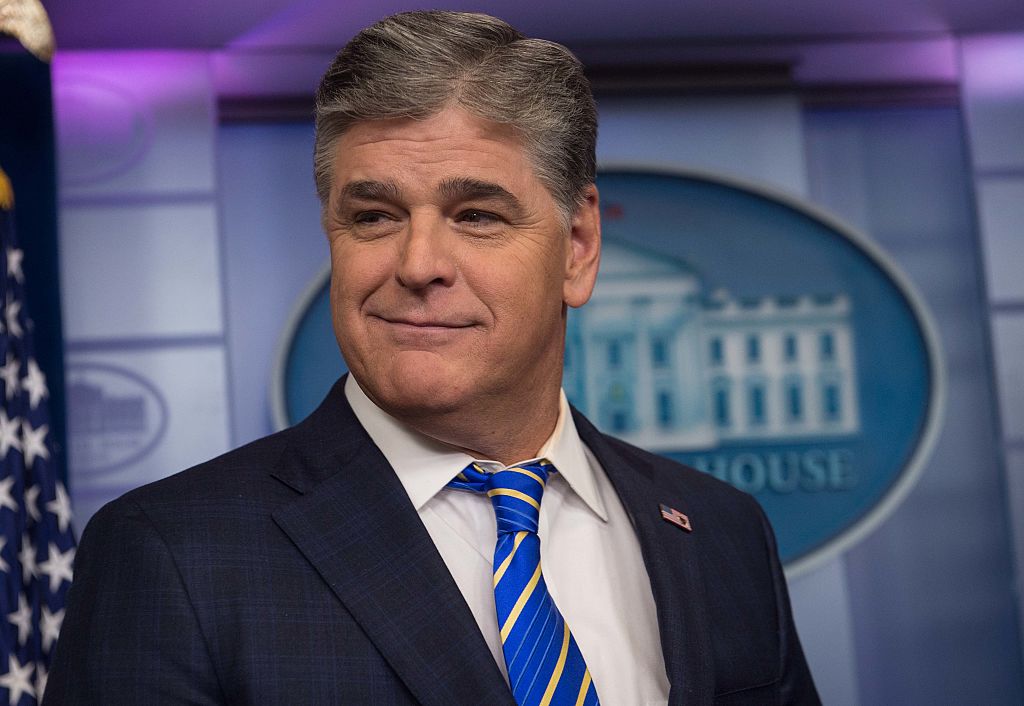 Sean Hannity in a blue jacket and striped blue tie grinning while at a White House event.