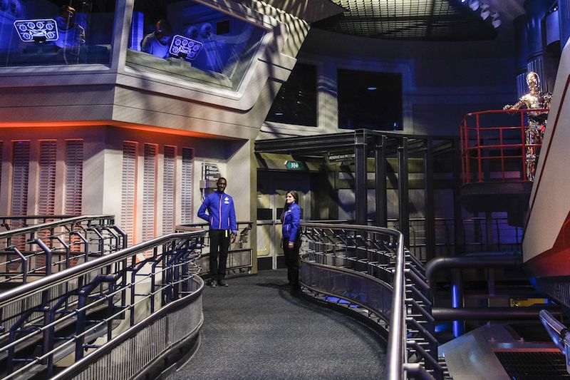 Two employees stand in a hallway at Star Tours The Adventure Continues Two employees stand in a hallway at Star Tours The Adventure Continues
