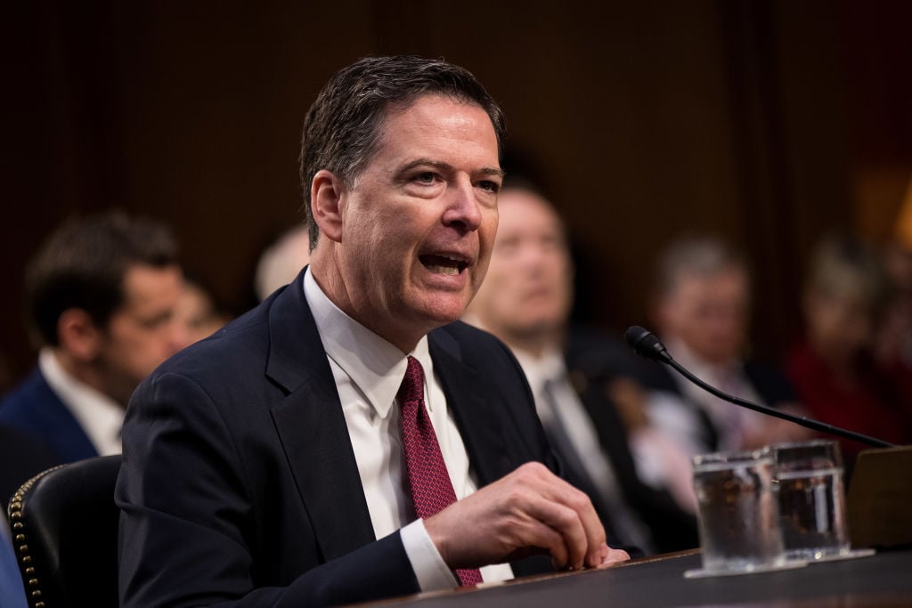 James Comey testifying in a dark suit and a red tie James Comey testifying in a dark suit and a red tie