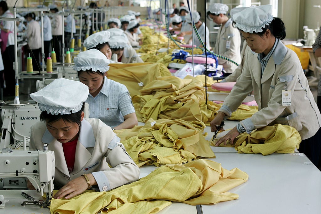 women in white work on yellow fabric in an assembly line