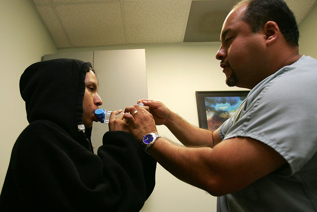 Asthma program director Alex Aldrete teaches 15-year-old Jesus Ayala the proper use of the new albuterol sulphate inhaler through a holding chamber at the Venice Family Clinic.