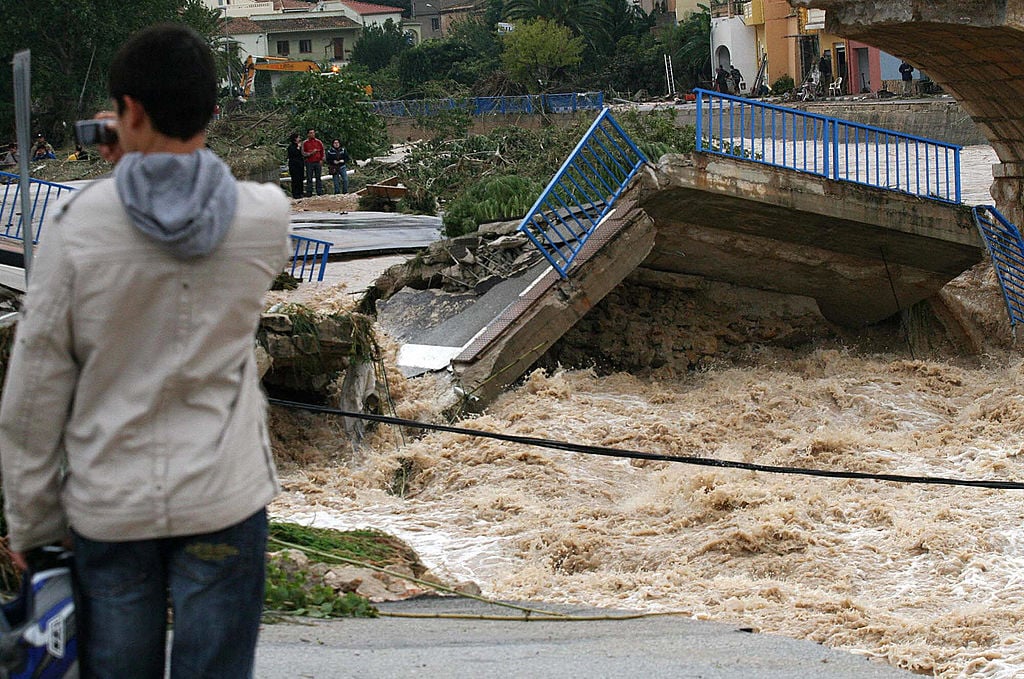 A man looks at a bridge destroyed by flooding. A man looks at a bridge destroyed by flooding.