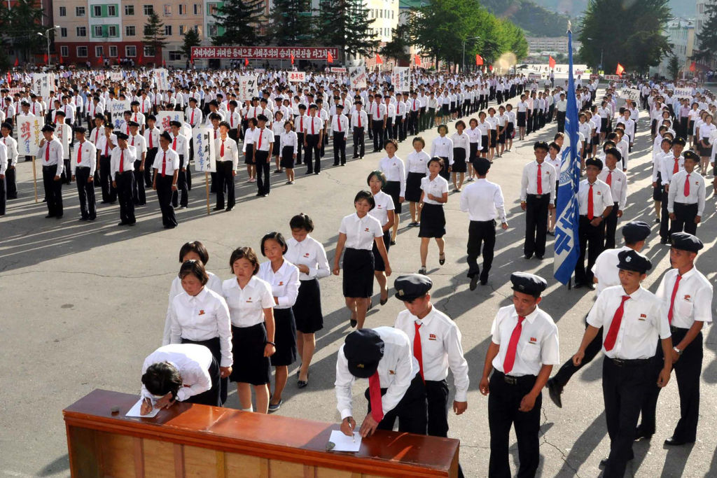 north korea students in white and red ties lining up to sign petitions