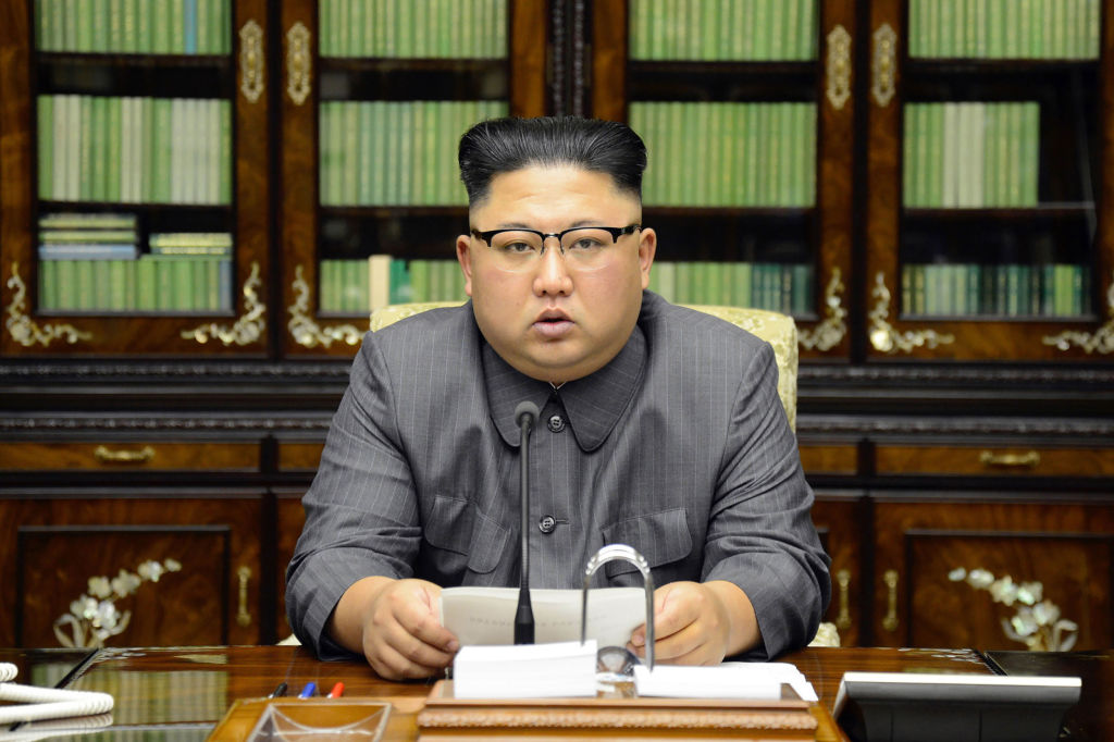 Kim Jong Un giving a statement at a desk with books behind him