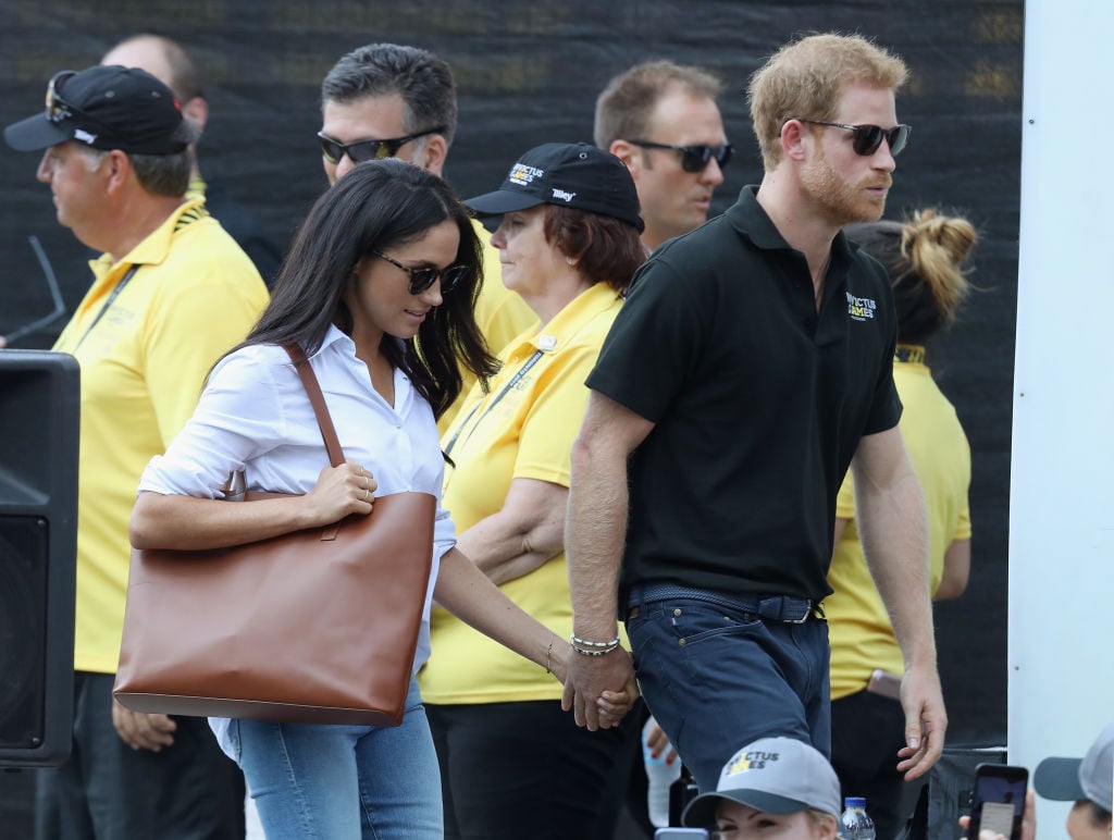 Meghan Markle and Prince Harry holding hands and walking together.